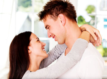 Young couple romancing while standing by window at home