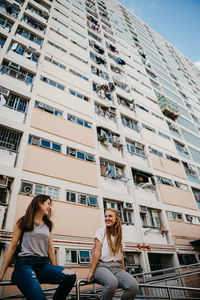 Friends sitting against buildings in city