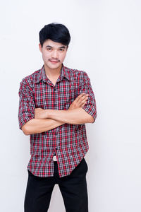 Portrait of young man standing against white background