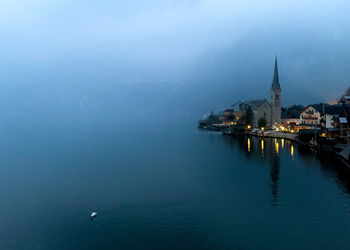 Sea by buildings in city against sky
