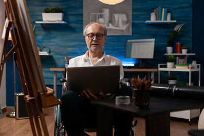 Young man using laptop while sitting on table