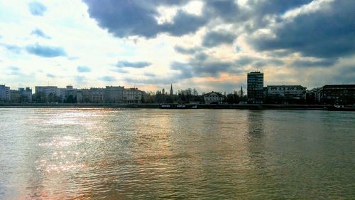 River by buildings in city against sky