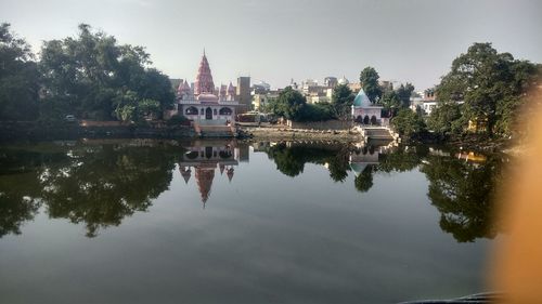 Reflection of buildings and trees in lake against sky