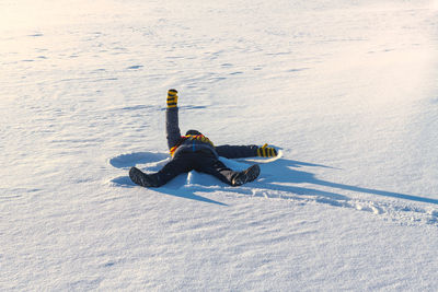 Rear view of man surfing on snow covered landscape