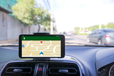 Close-up of smart phone displaying map on dashboard of car