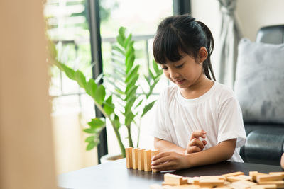 Young woman looking down while sitting on table