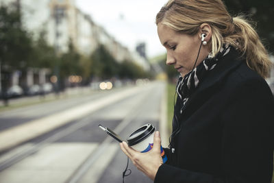 Profile view of mid adult businesswoman using mobile phone on city street