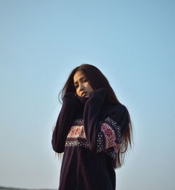 Low angle view of woman standing against clear blue sky