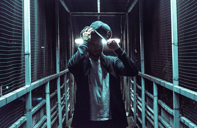 Man holding metal while standing in illuminated building