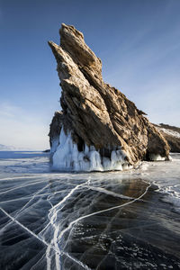 Rock formation by sea against sky