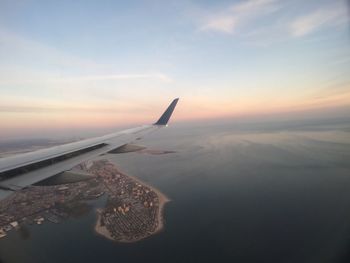 Close-up of airplane wing over sea against sky