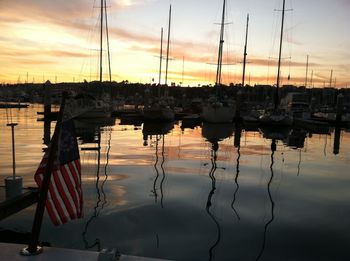 Sailboats moored at harbor against sky during sunset