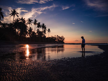 Silhouette man standing at beach during sunset