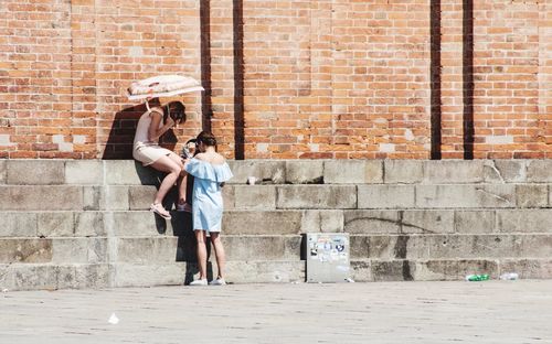 Full length of couple standing against brick wall