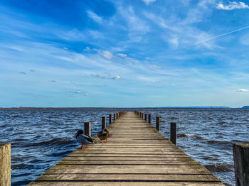 Wooden pier over sea against sky