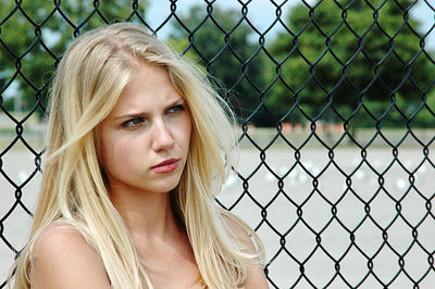 Portrait of beautiful young woman in chainlink fence