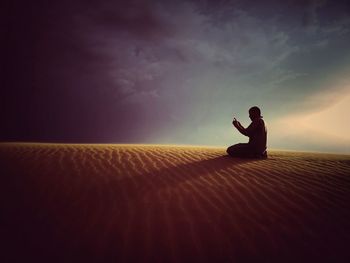 Side view of silhouette man sitting on skateboard against sky