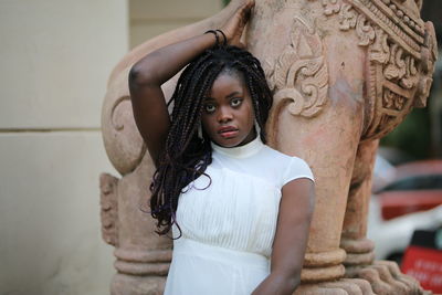 Portrait of young woman standing against wall