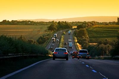 Cars on road against sky during sunset