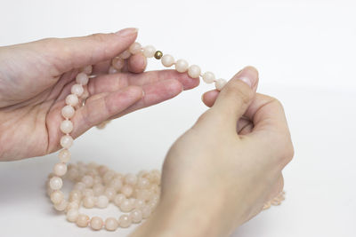 Close-up of woman hand holding ring over white background