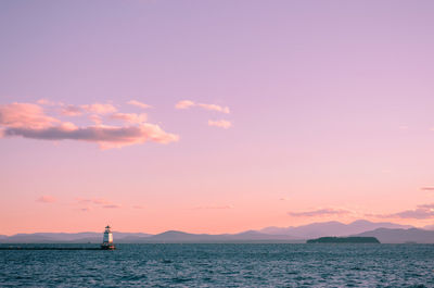 Boats sailing in sea at sunset