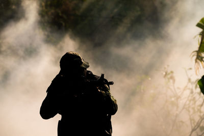 Silhouette soldier against smoke outdoors