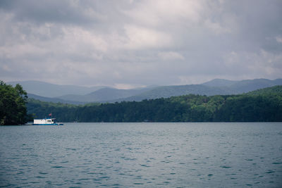 Scenic view of lake and mountains against cloudy sky