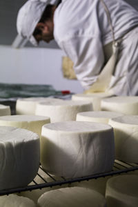 Close-up of cheese arranged while man working at factory