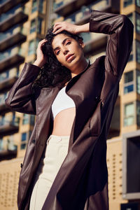 Portrait of young woman standing against wall