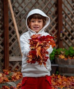 Portrait of cute girl holding leaves outdoors