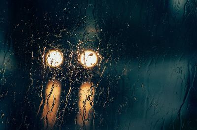 Waterdrops on glass with view of headlights at night