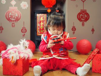 Cute girl in traditional clothing with decoration sitting at home