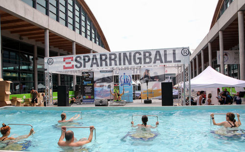 People swimming in pool against buildings