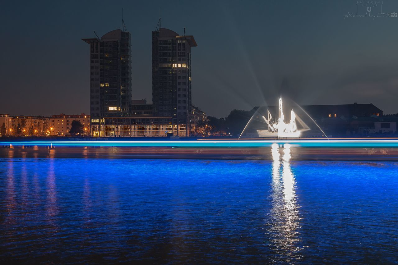 illuminated, night, architecture, built structure, water, building exterior, waterfront, long exposure, travel destinations, river, city, outdoors, no people, modern, motion, skyscraper, sky, cityscape