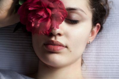 Directly above shot of young woman with pink flower lying on bed