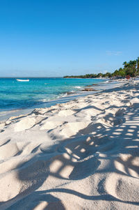 Scenic view of beach against clear blue sky