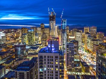 Illuminated cityscape against blue sky at night