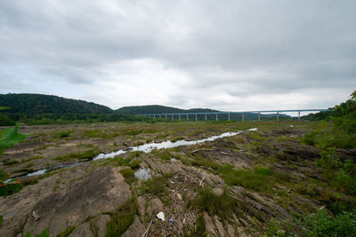 A huge sprawling landscape covered in rock formations and plants with the norman wood bridge behind 