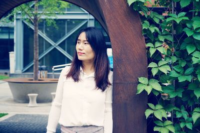 Portrait of woman standing against plants