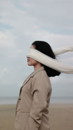 Side view of woman with blindfold standing on beach