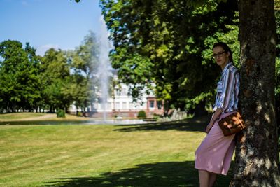 Portrait of young woman standing against trees