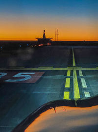 View of airport runway against sky during sunset