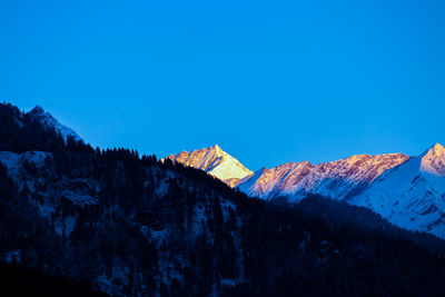 Scenic view of snowcapped mountains against clear blue sky