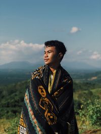 Young man looking away against sky