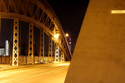 Illuminated light trails on road by building at night