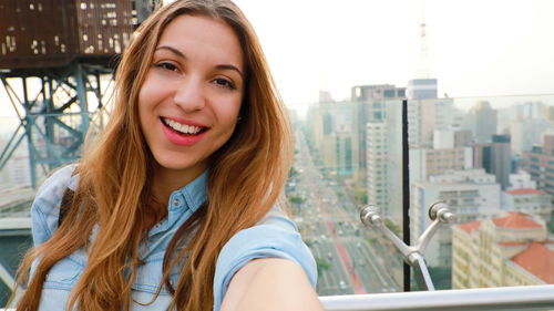 Portrait of smiling young woman standing by window