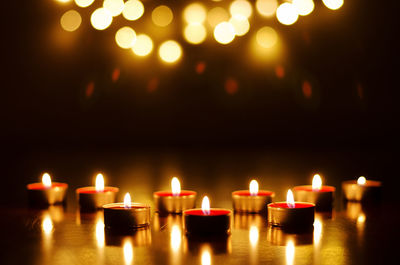 Burning candles with festive bokeh on black background. holiday concept, prayer and hope.