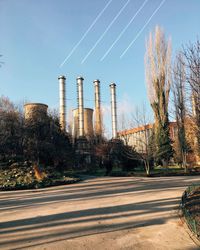 Low angle view of smoke stacks with vapor trails against sky