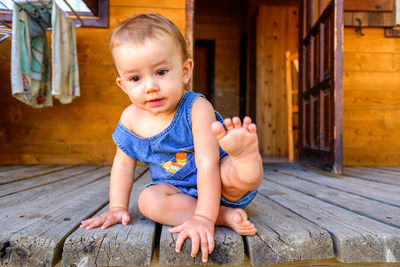 Portrait of cute baby girl sitting on wood