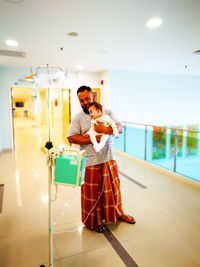 Father carrying cute daughter while standing in hospital corridor